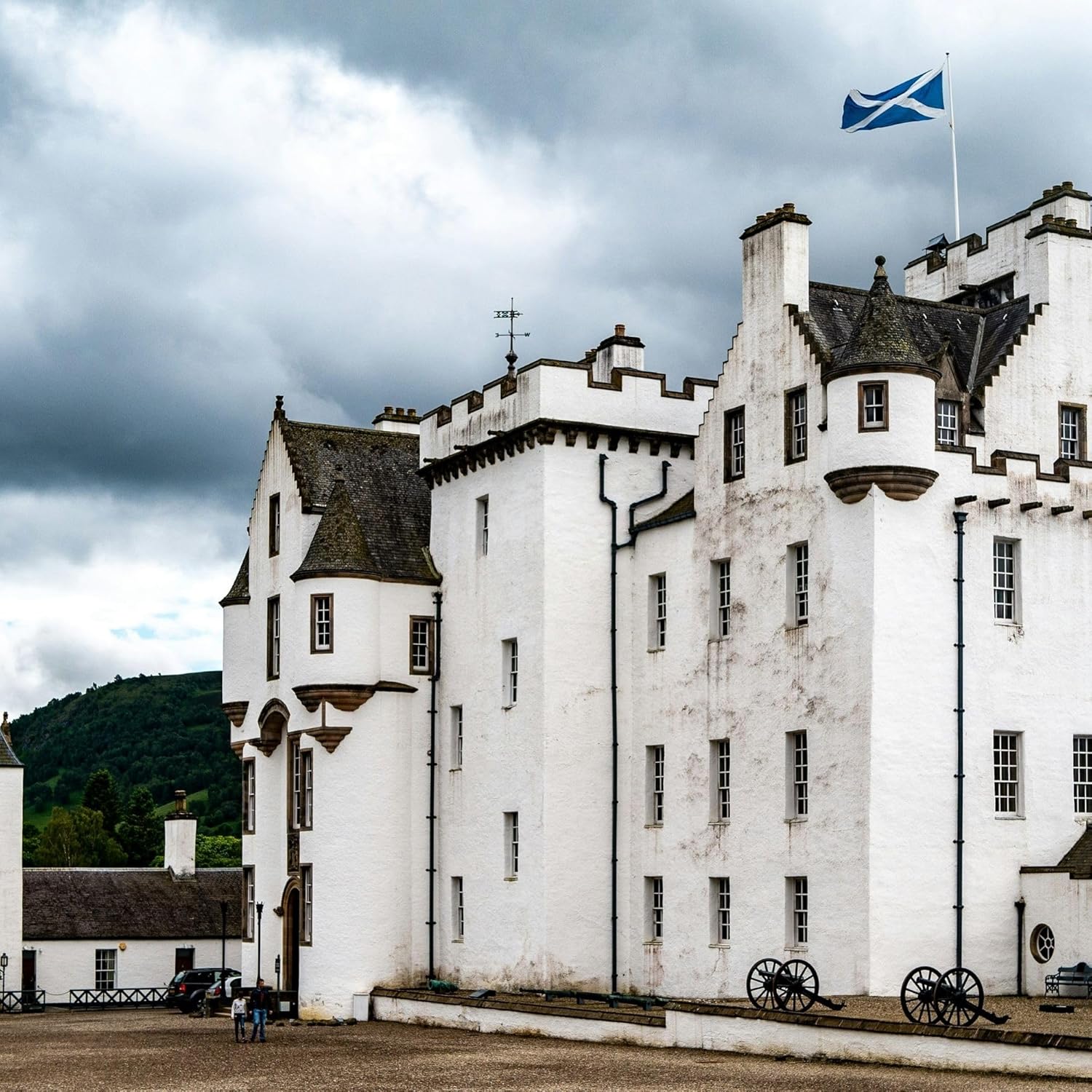 Scotland saltire flying from a flagpole above a Scottish castle under heavy cloud