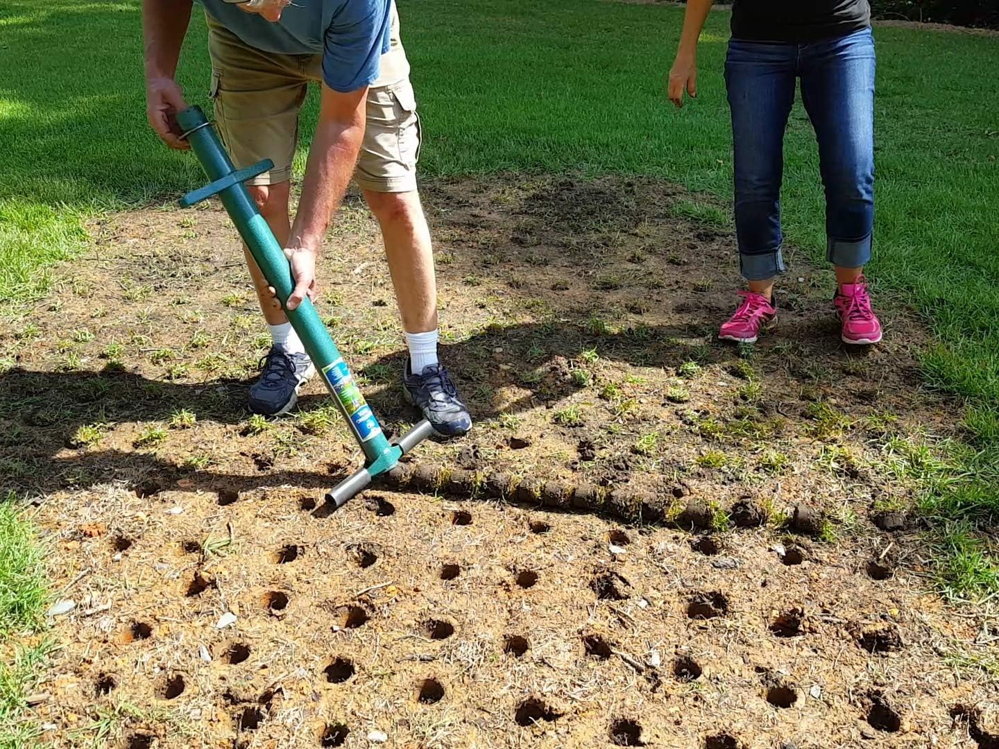 Gardener cutting a grid of planting holes across a bare patch of ground with the ProPlugger