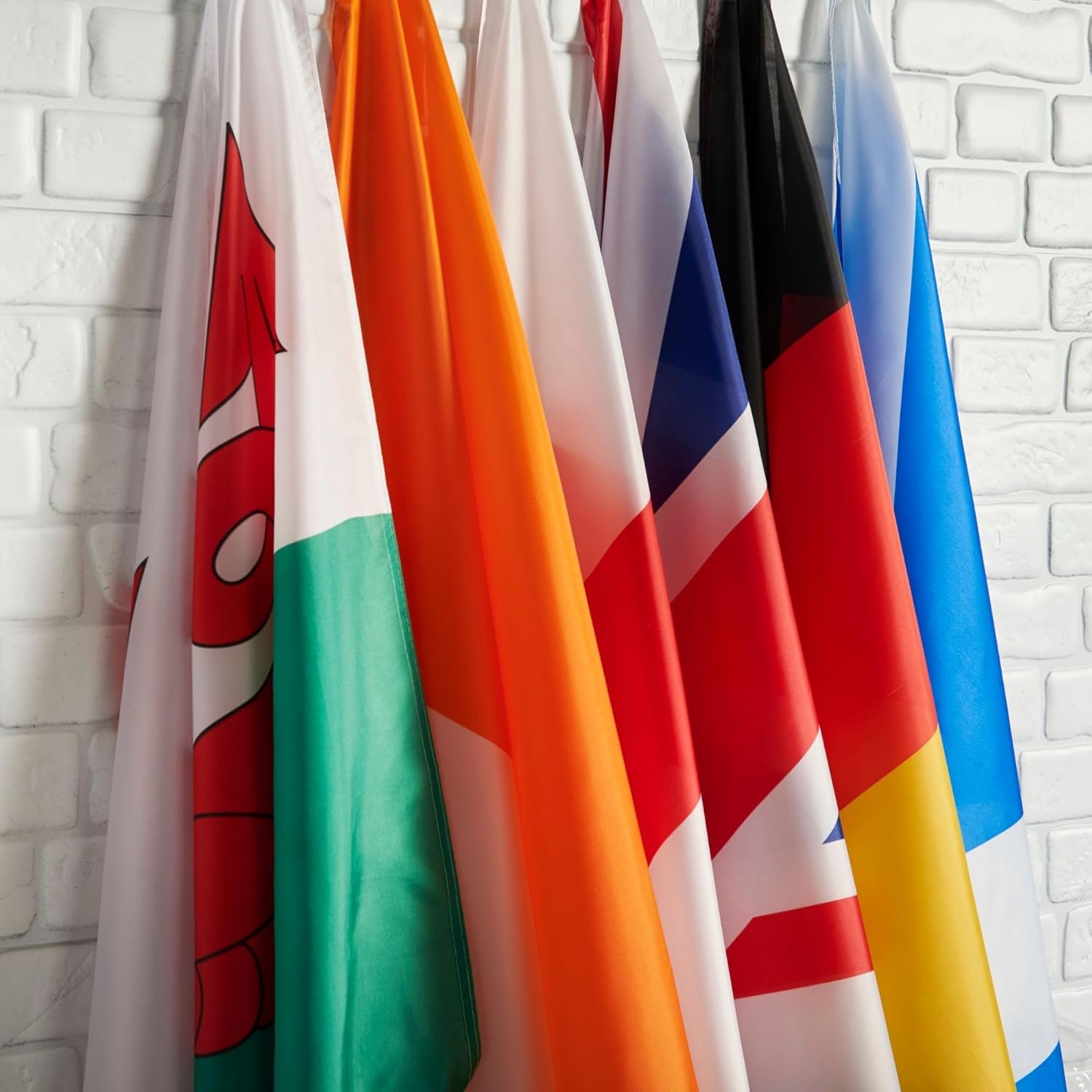 Runesol flag range hanging against a white brick wall showing the lightweight polyester fabric
