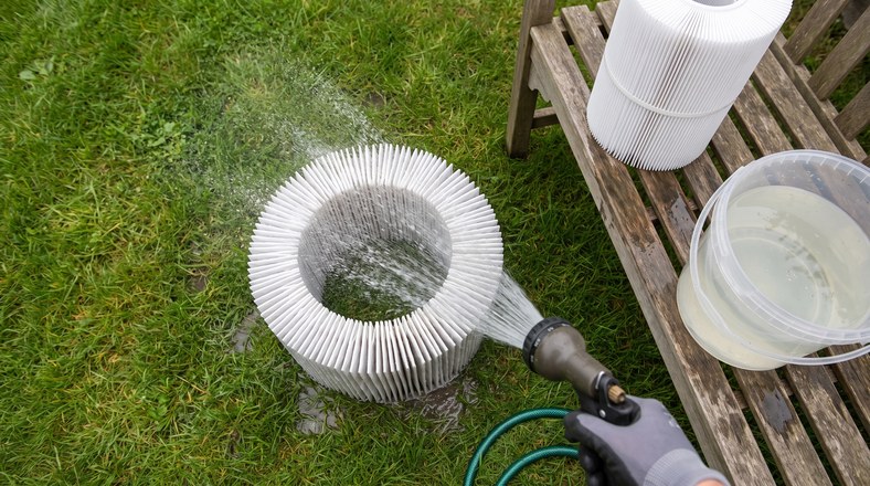 Rinsing a pleated hot tub filter cartridge with a garden hose to stop hot tub water going cloudy