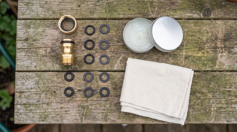 Replacement O-rings and washers laid out next to a dismantled garden hose connector