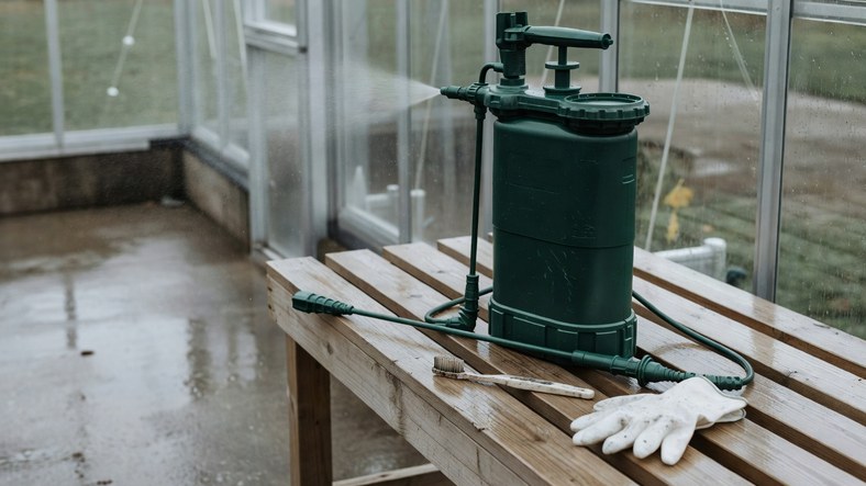 Pump-action pressure sprayer used to disinfect greenhouse staging and aluminium frame channels in autumn