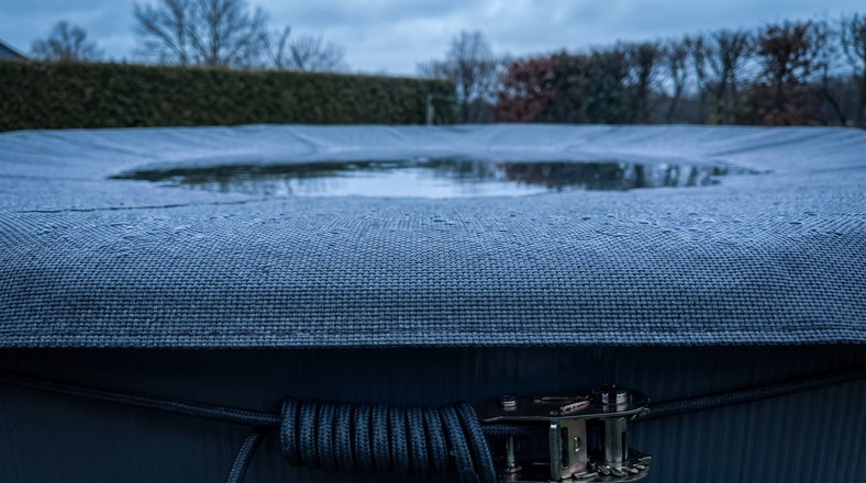 Winter cover pulled tight over an above ground pool with the water level lowered for a UK winter